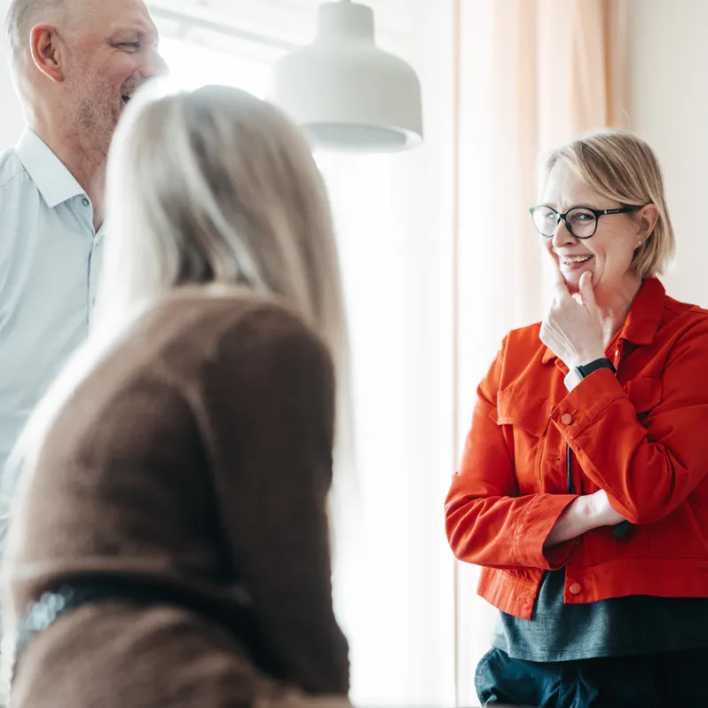 Grupp med fem människor. Kvinna i fokus med röd jacka, glasögon och ljust hår.