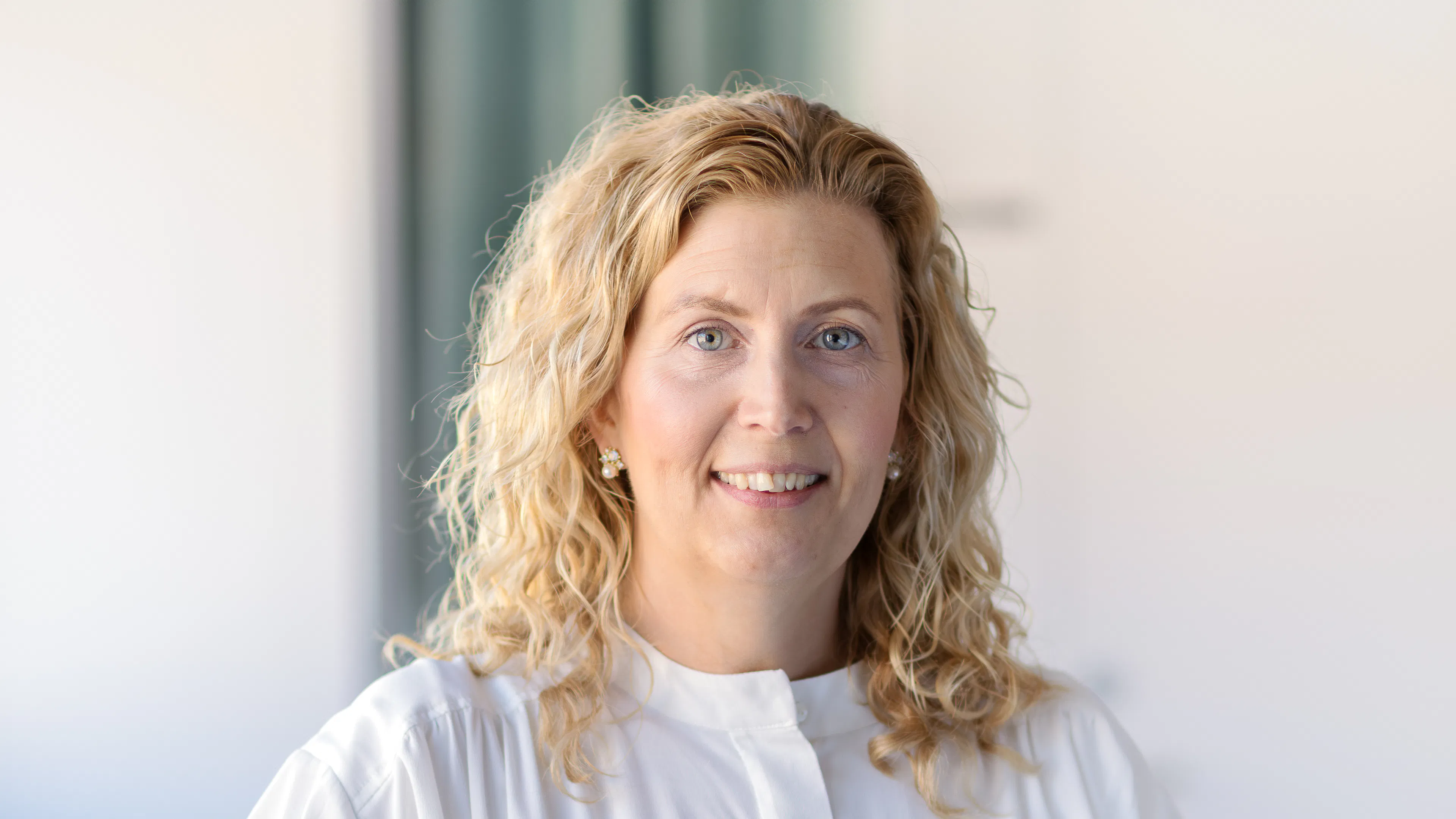 Frau mit hellem Haar und weißer Bluse.