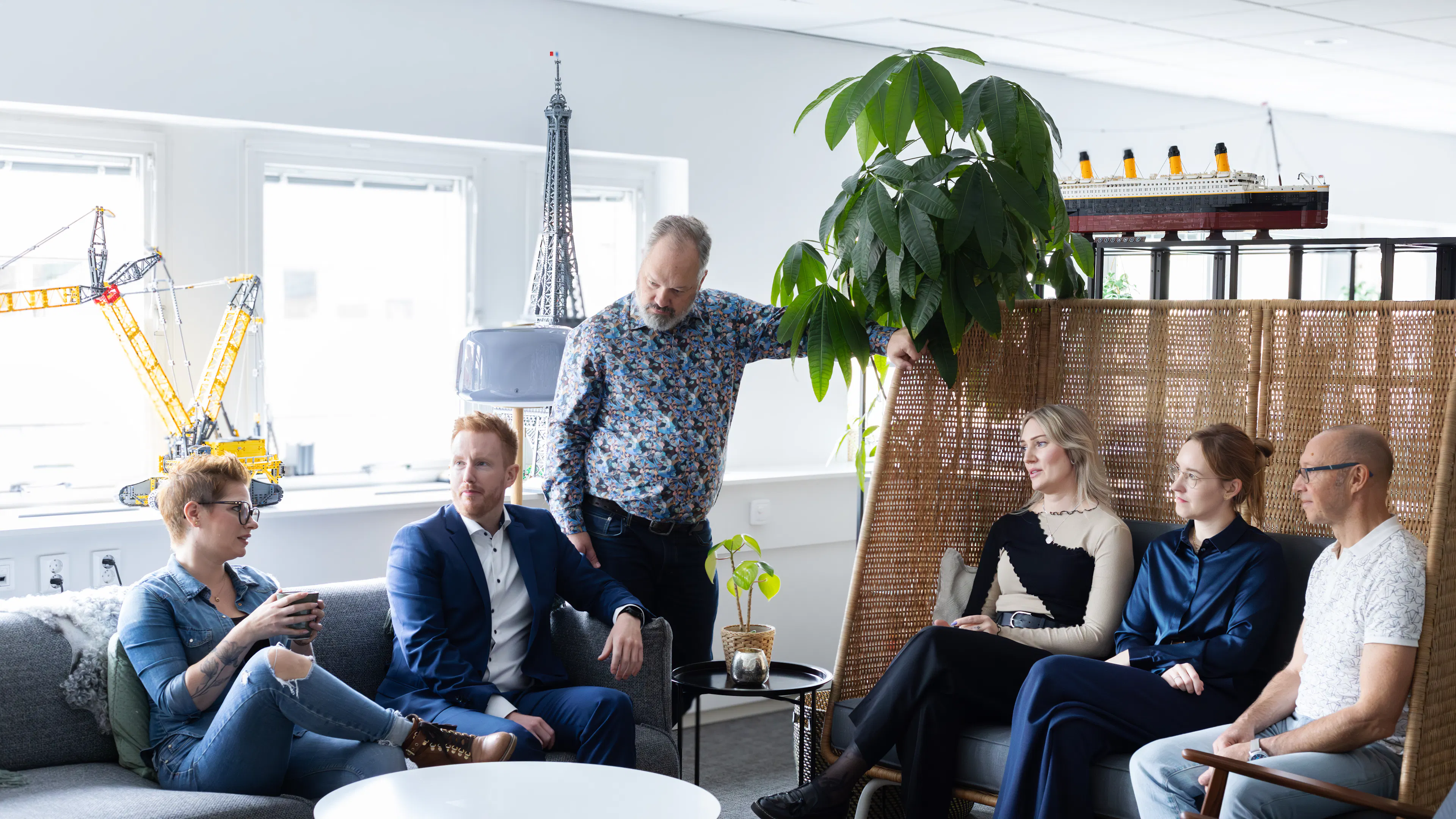 Sex personer som sitter i en soffgrupp och pratar med varandra.