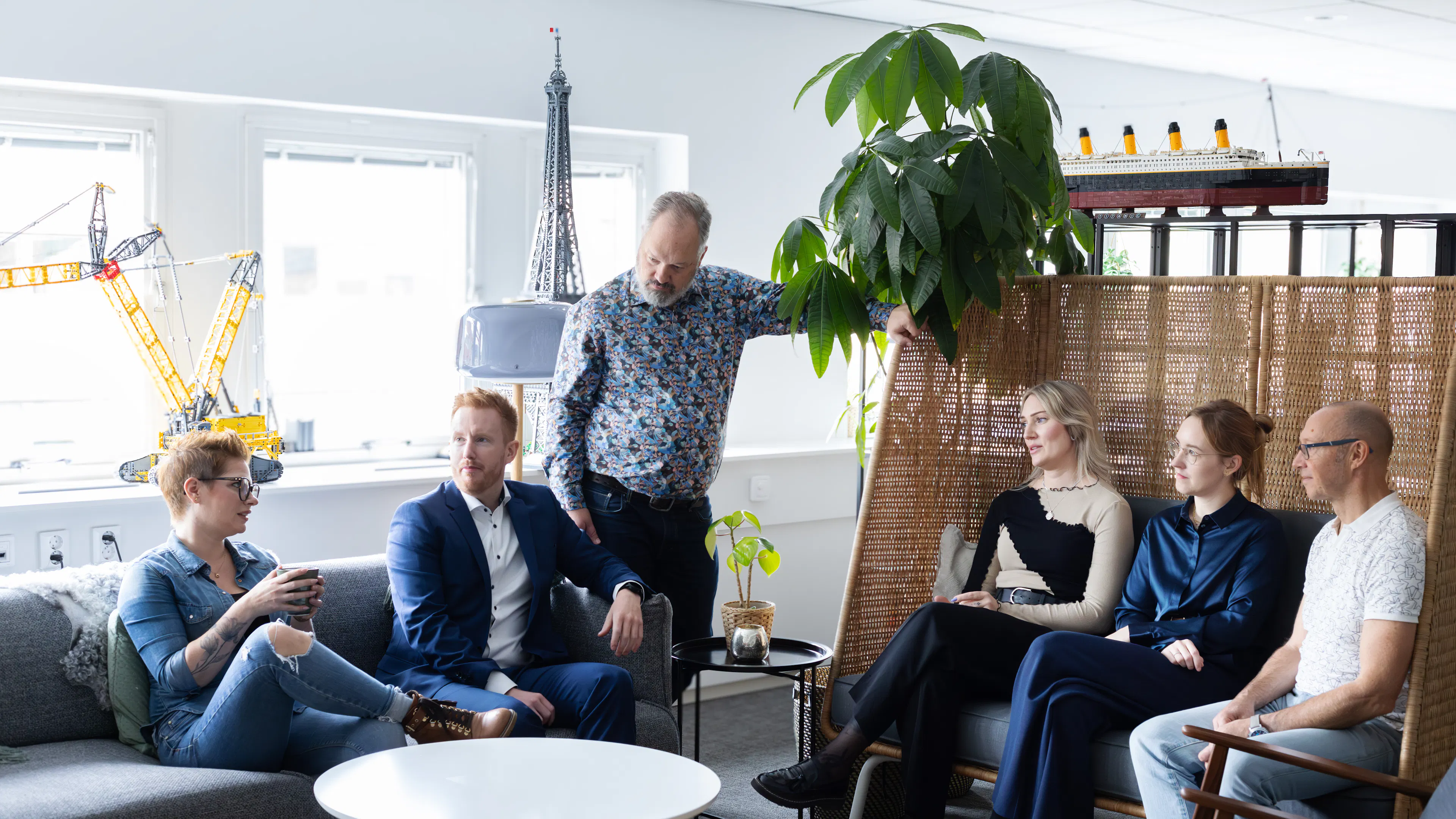 Sex personer som sitter i en soffgrupp och pratar med varandra.