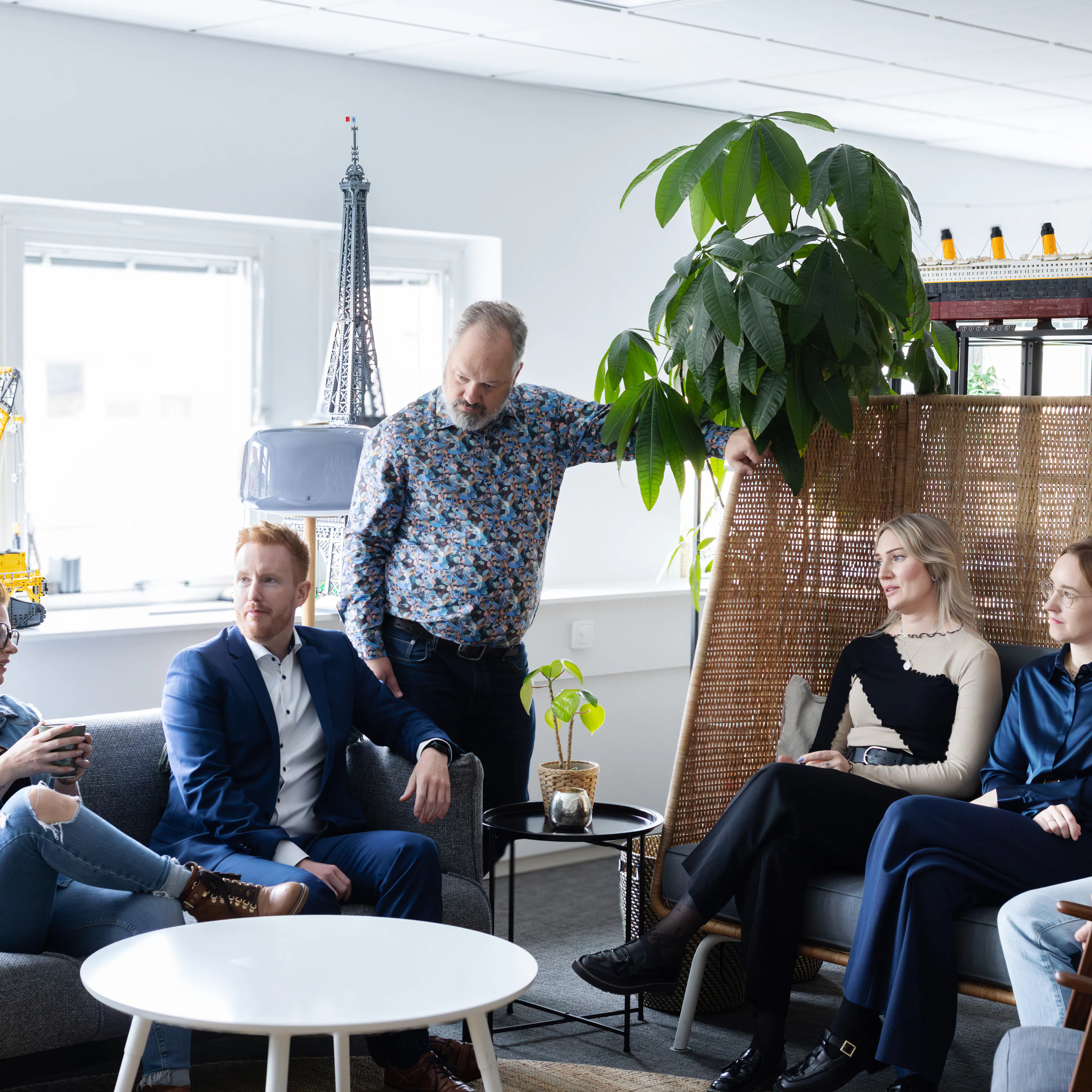 Sex personer som sitter i en soffgrupp och pratar med varandra.