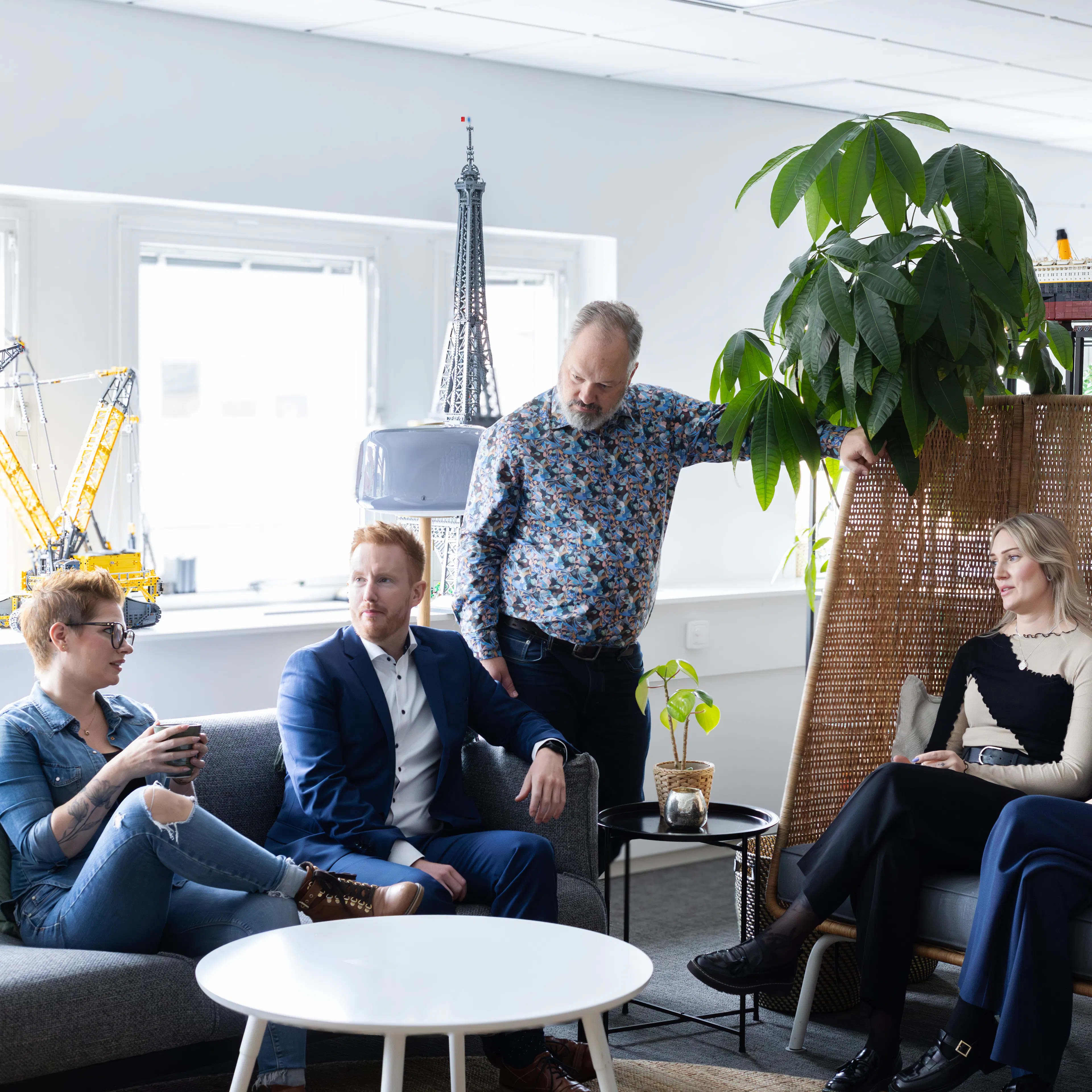 Sex personer som sitter i en soffgrupp och pratar med varandra.