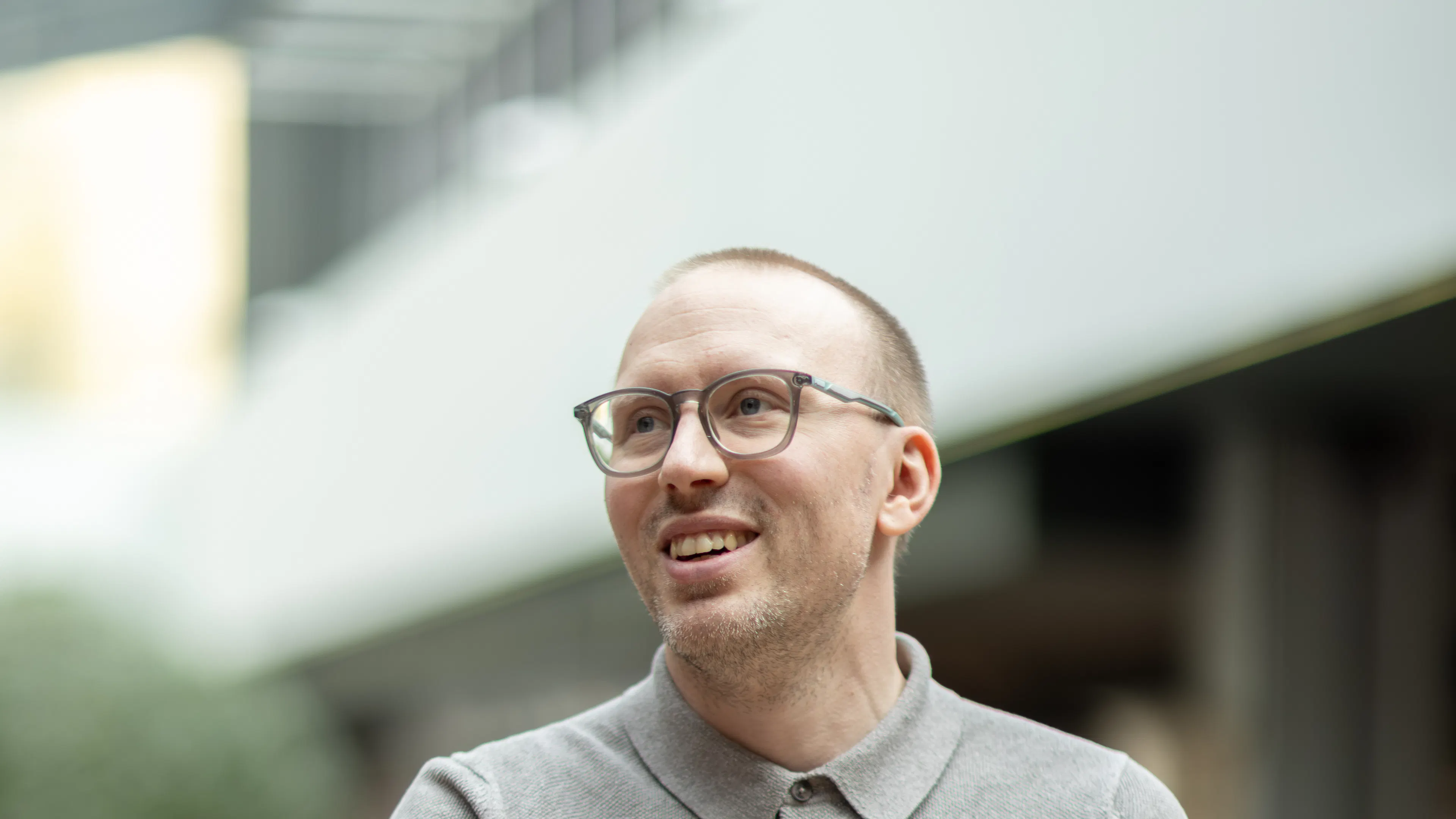 Mann in grauem Poloshirt, mit kurzem Haar und Brille.
