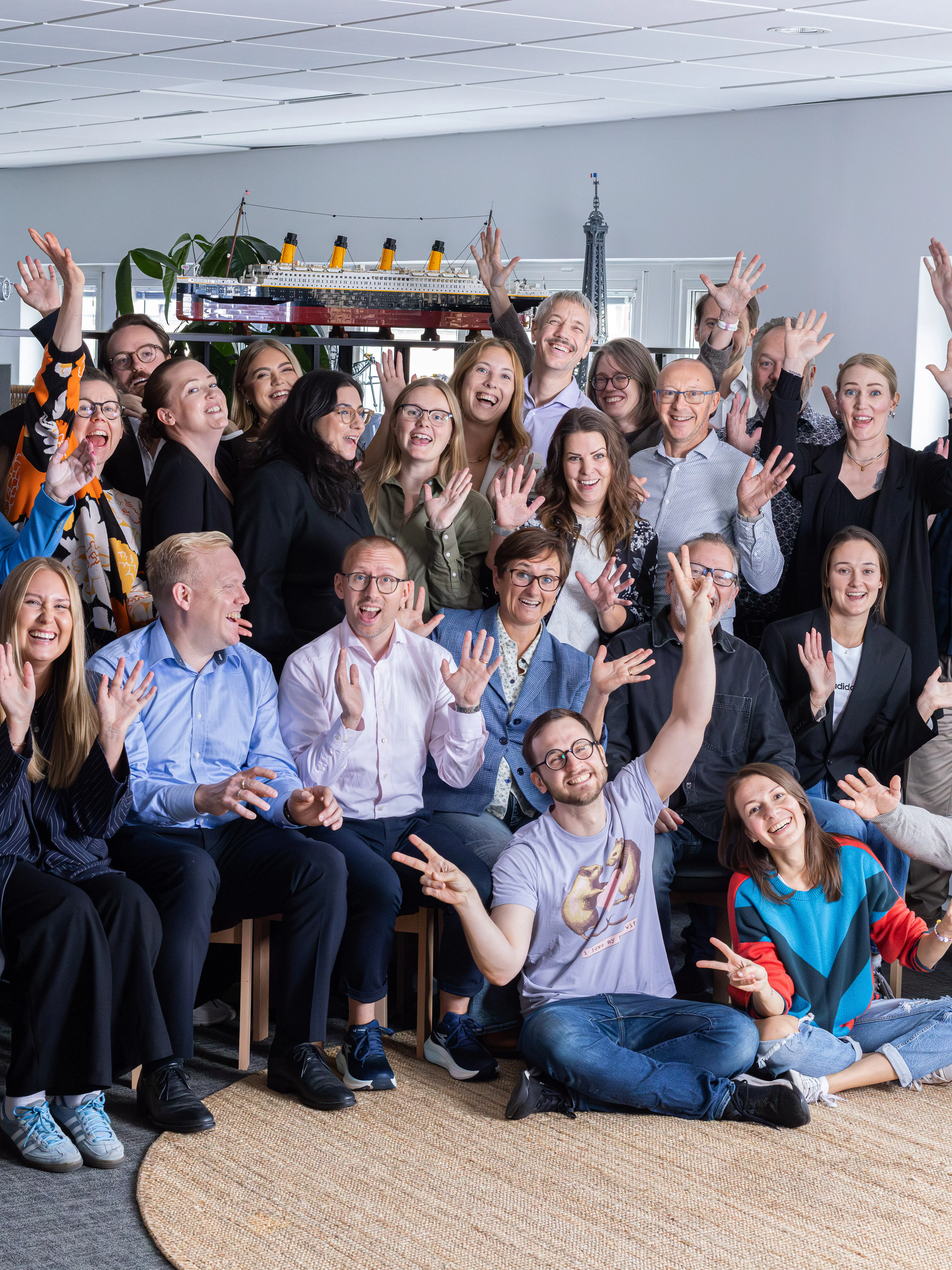 Gruppbild med en massa glada människor som vinkar.