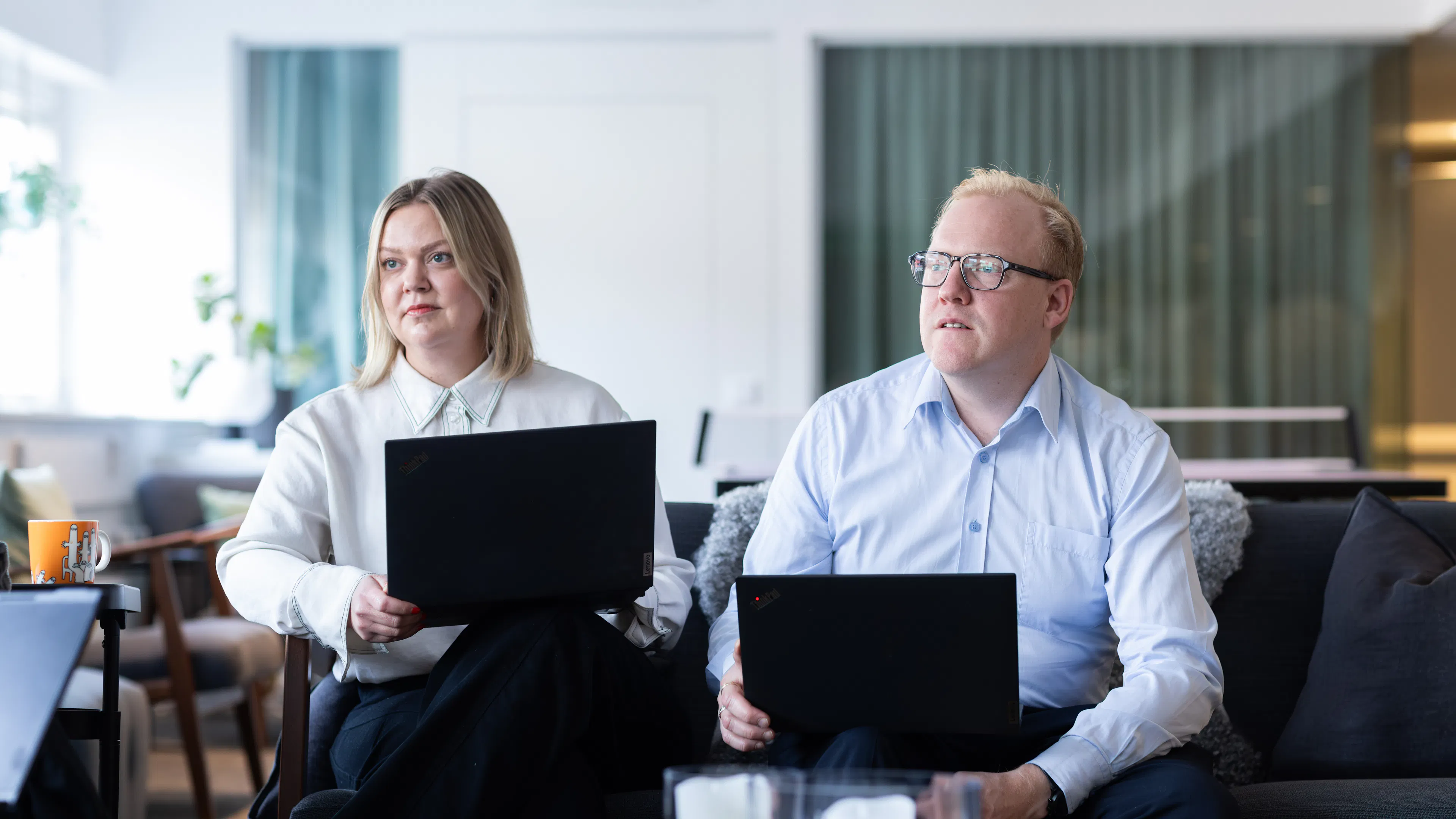 Två personer som sitter i en soffa med laptop i knät.