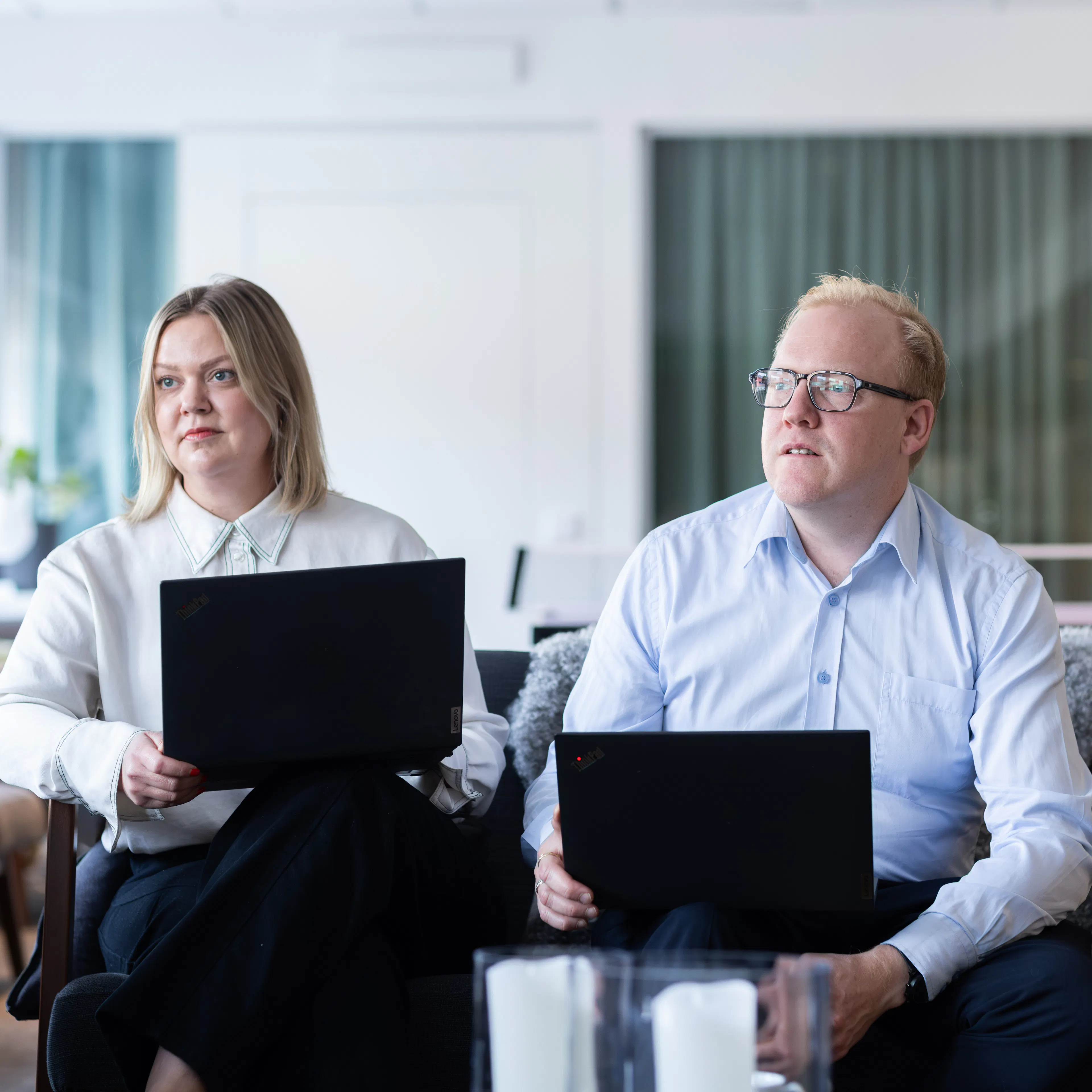 Två personer som sitter i en soffa med laptop i knät.