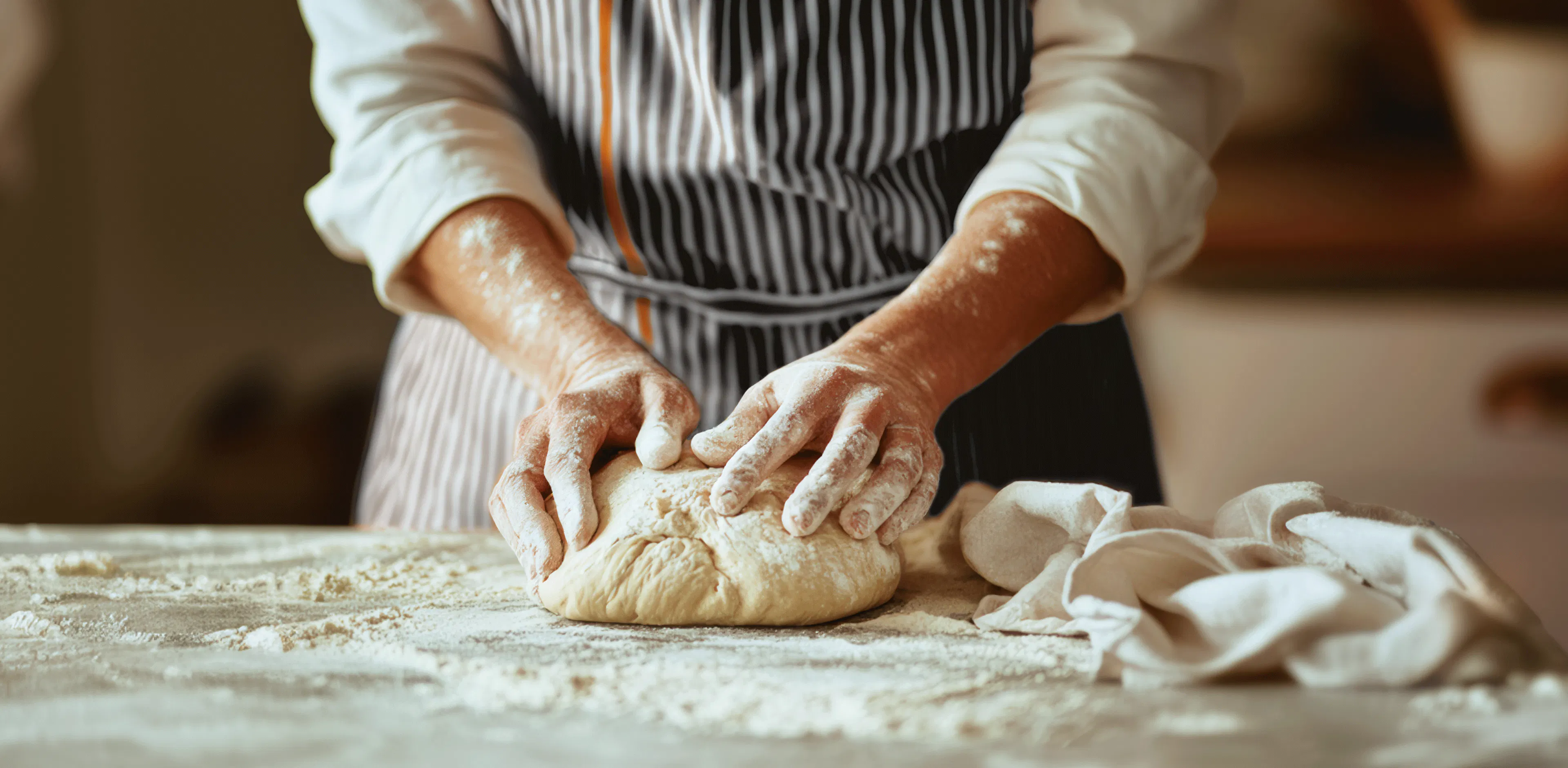 Person working on a dough with  Crosta Mollica’s striped apron.