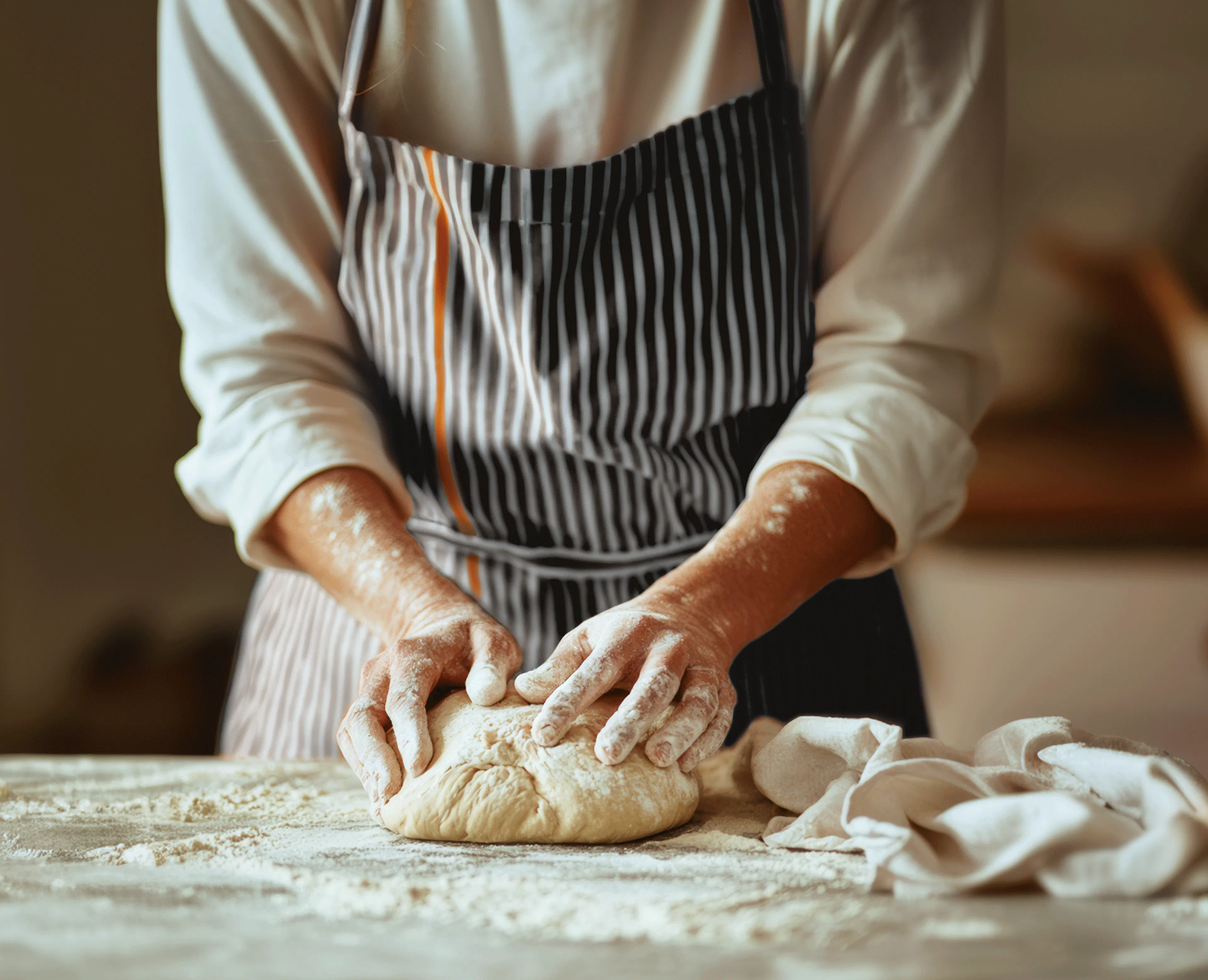 Person working on a dough with  Crosta Mollica’s striped apron.