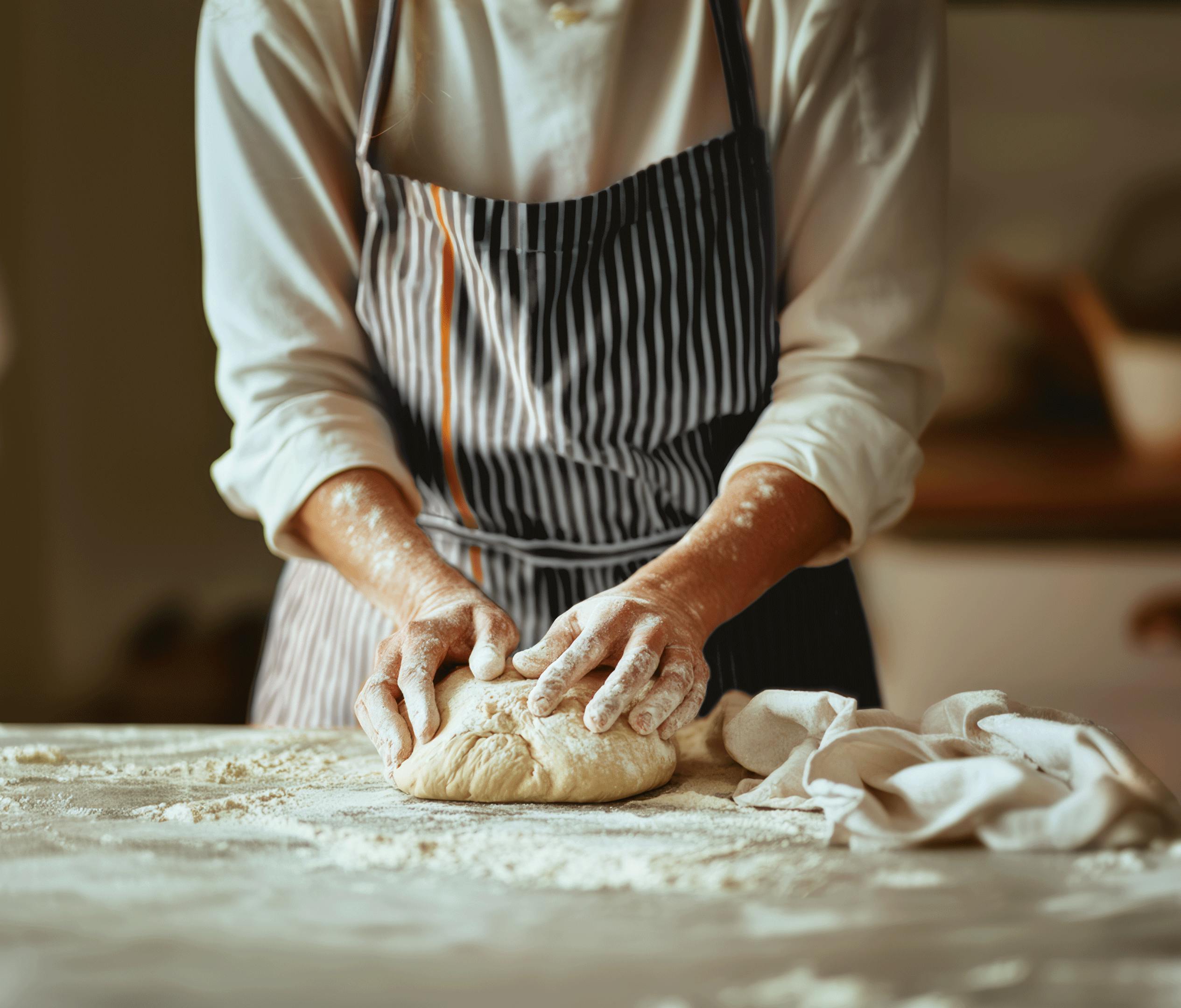 Person working on a dough with Crosta Mollica’s striped apron.