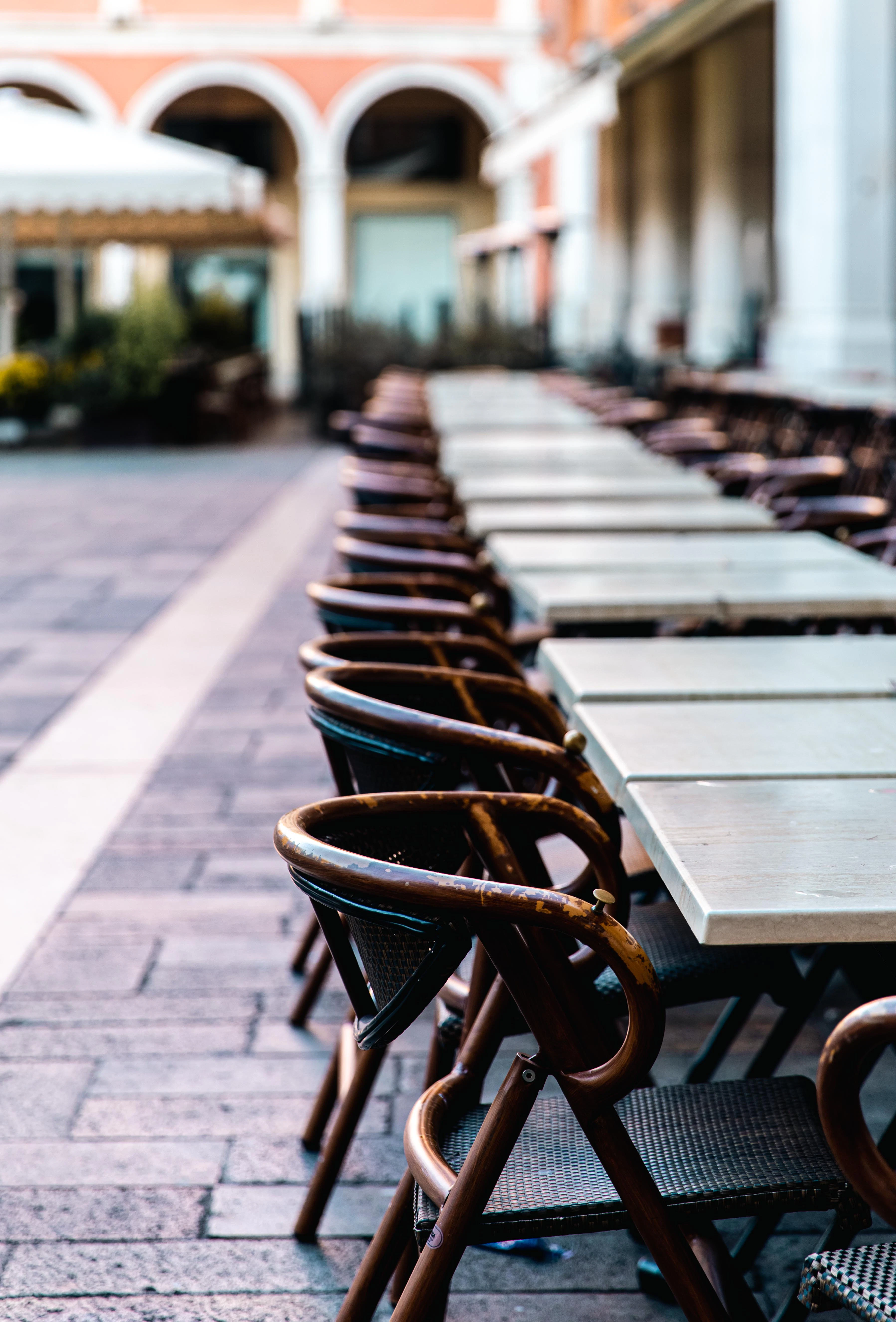A line of empty tables and chairs in a piazza.