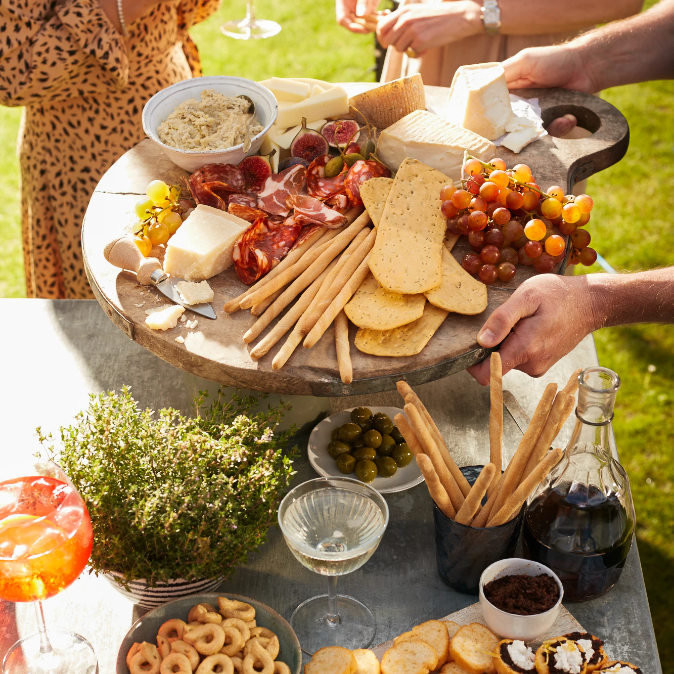 People reaching for food on an antipasti platter.
