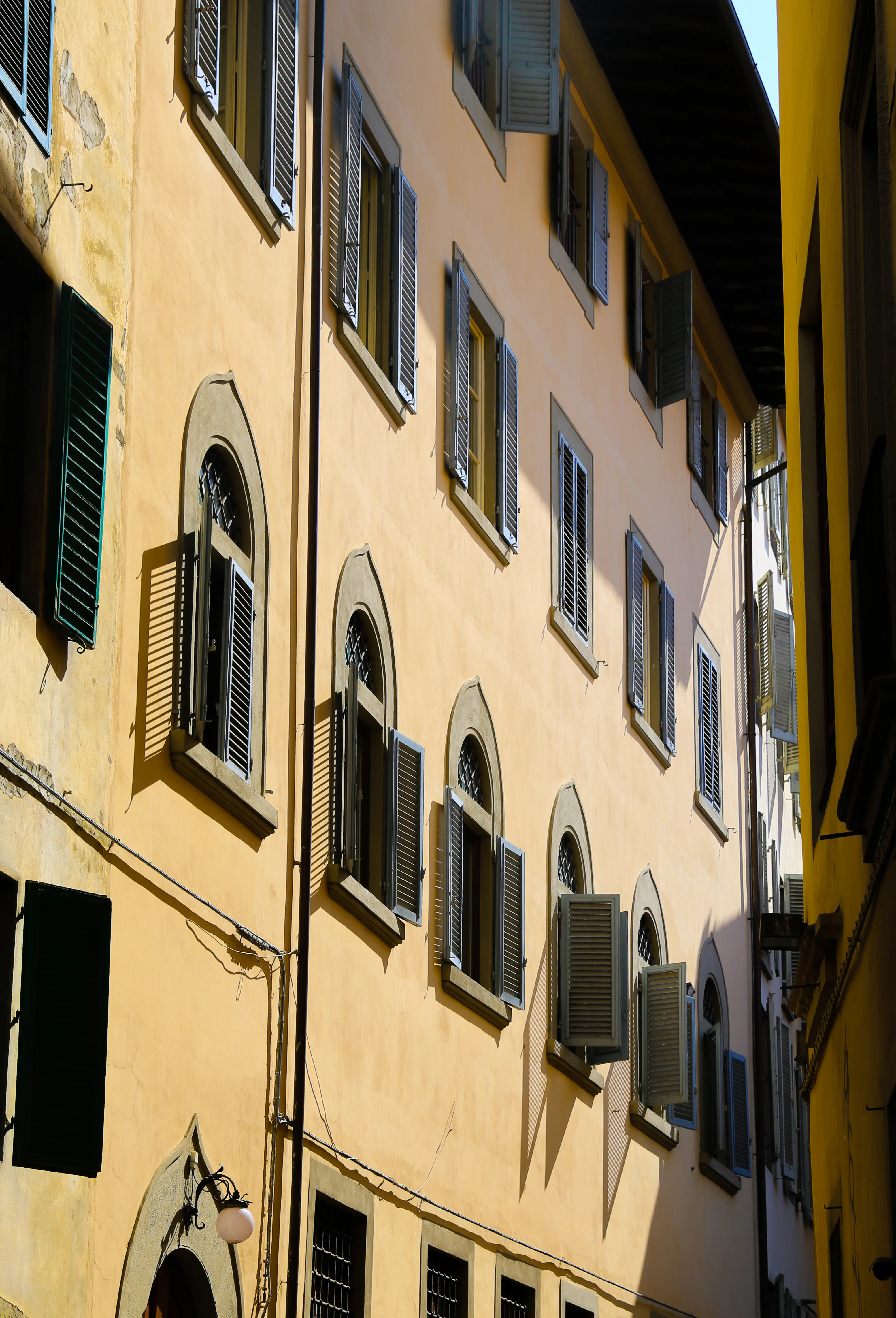 The side of a green building with windows and shutters.