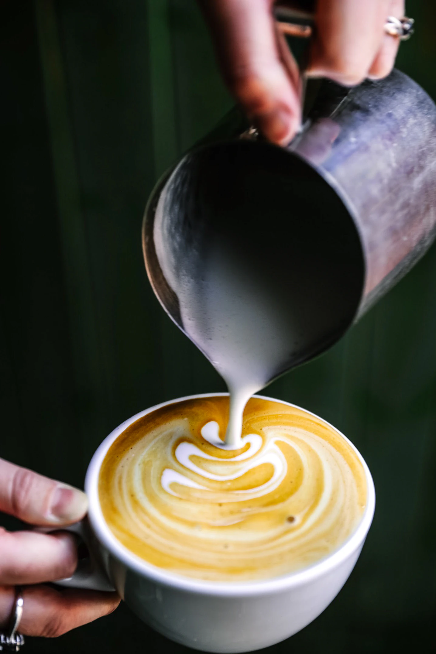 Frothy milk is being poured into a latte.