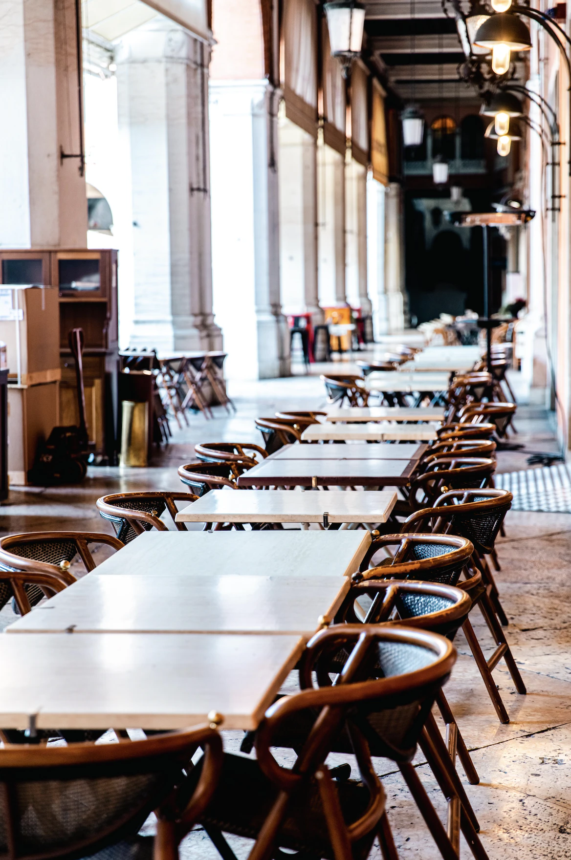 A line of tables and chairs sit under a archway.