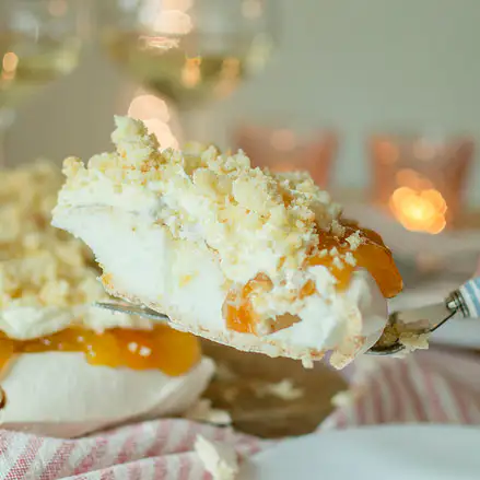 A slice of pavlova is being lifted up on a fork.