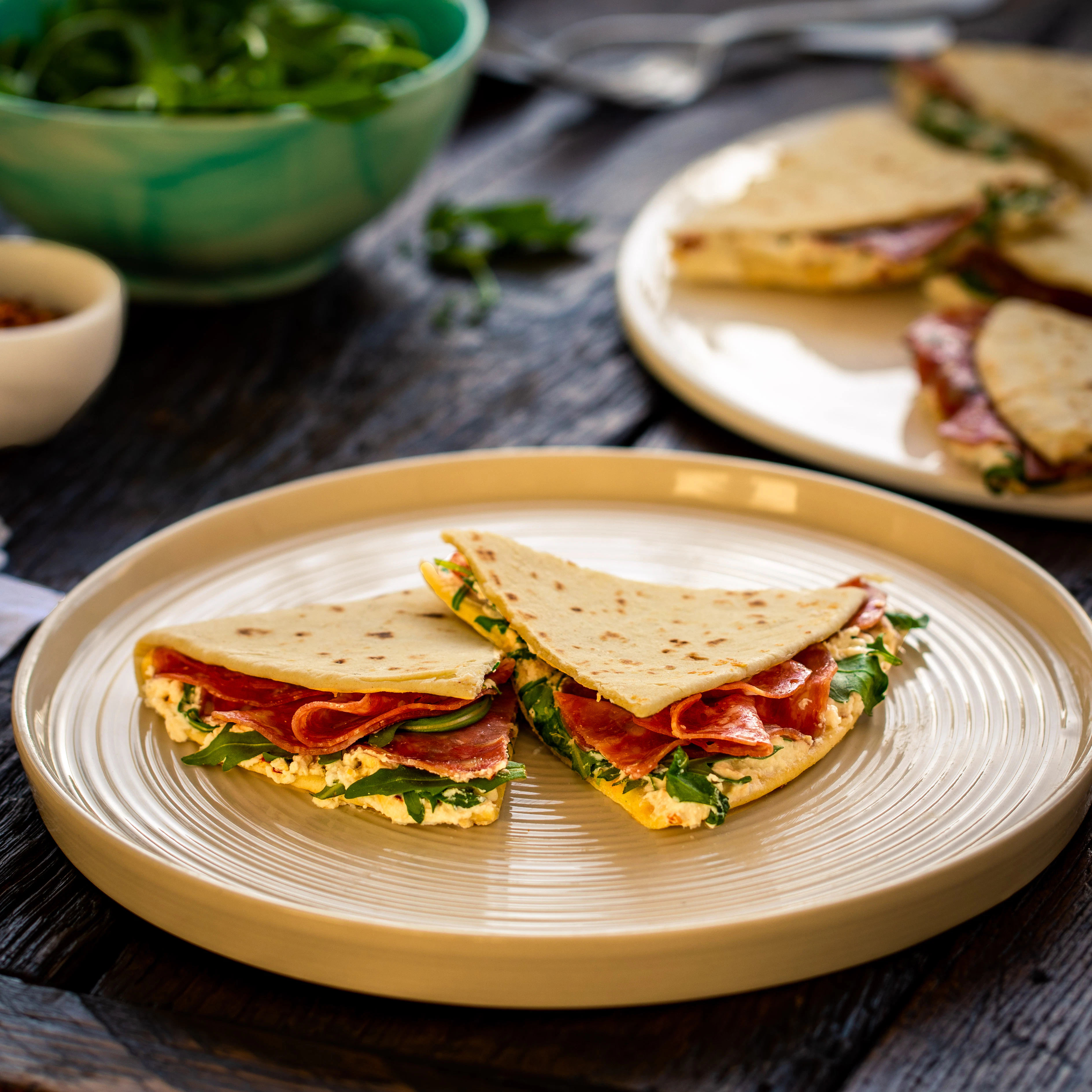 Piadina filled with Salami, Ricotta and Rocket on a table.
