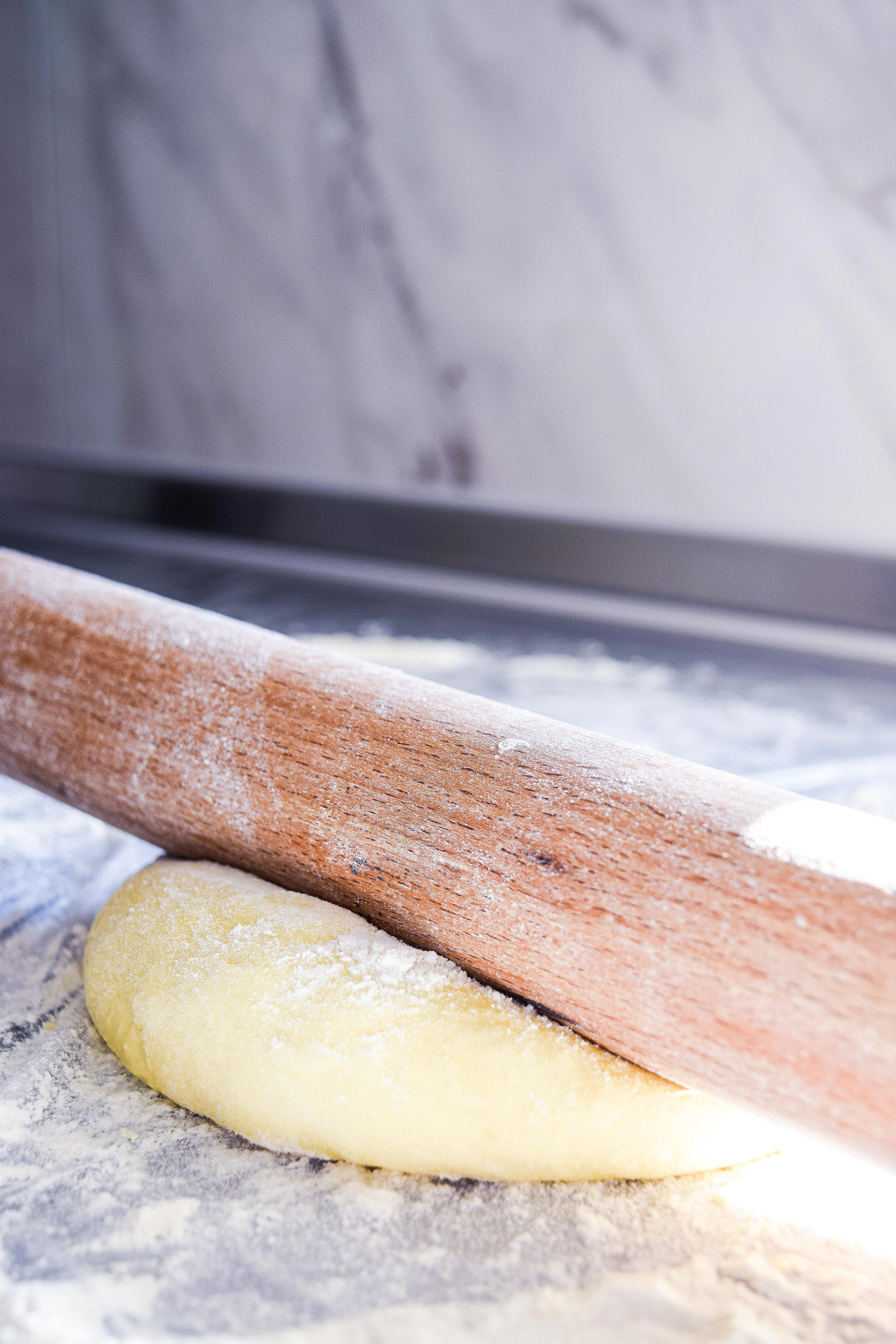 A rolling pin on top of a piece of dough.