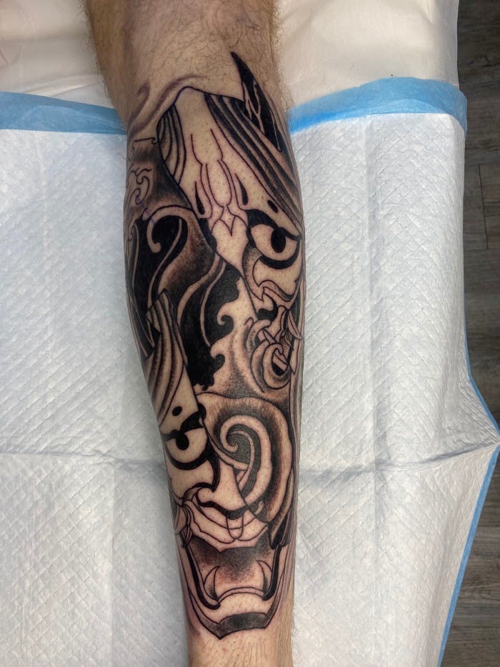 Tattoo of oni masks mixed with a tidal wave.