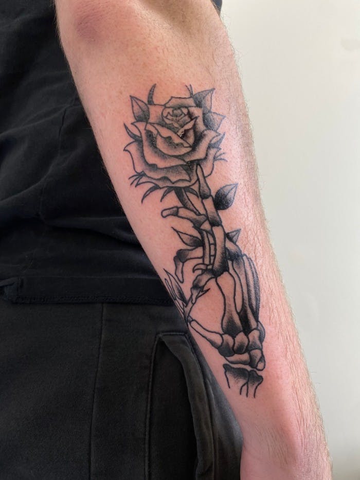 Tattoo of a skeleton hand holding a rose.