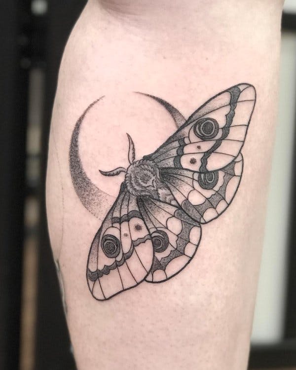 Tattoo of a moth with a crescent moon.