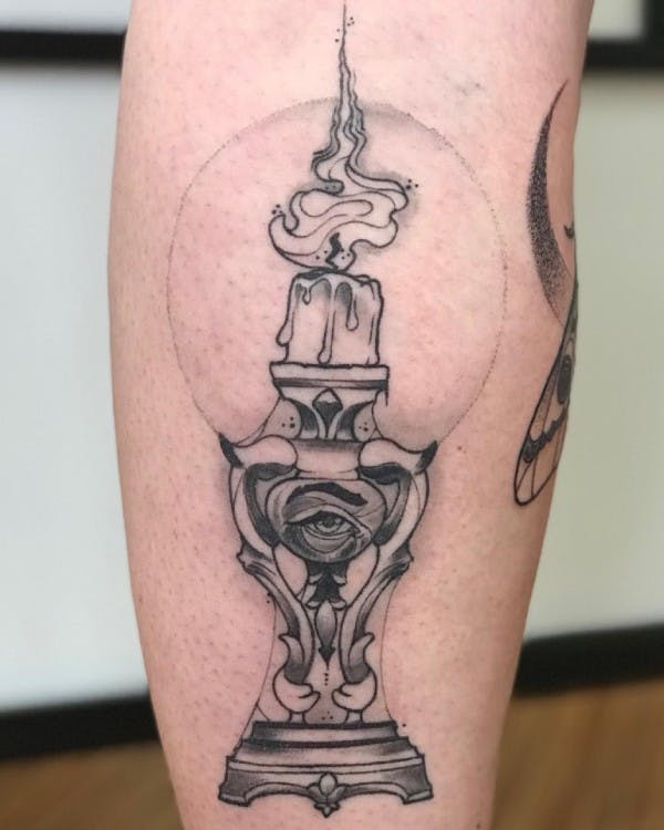 Tattoo of an intricate base crystalball with a lit candle inside.