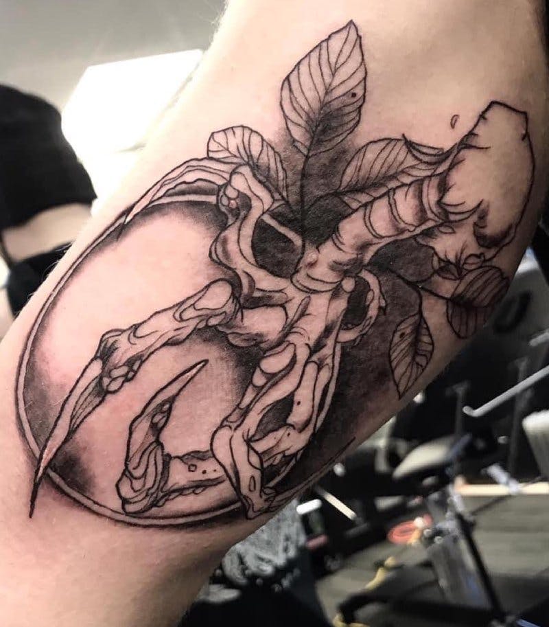 Tattoo of a skeleton hand grabbing a spherical object.