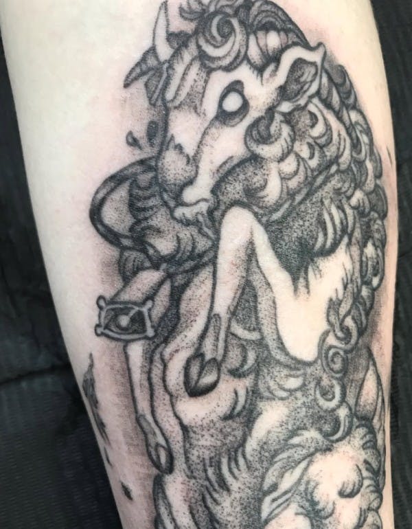 Tattoo of a fluffy upright cattle wearing a cowbell.