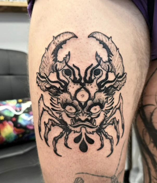 Tattoo of a crab with an oni face underbelly.