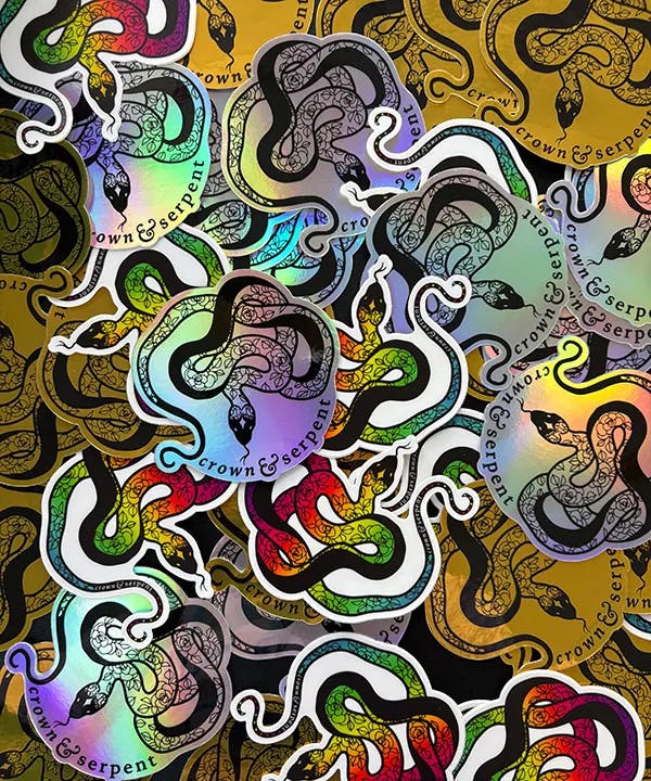 A holographic collection of Crown & Serpent's logo stickers in various colors.