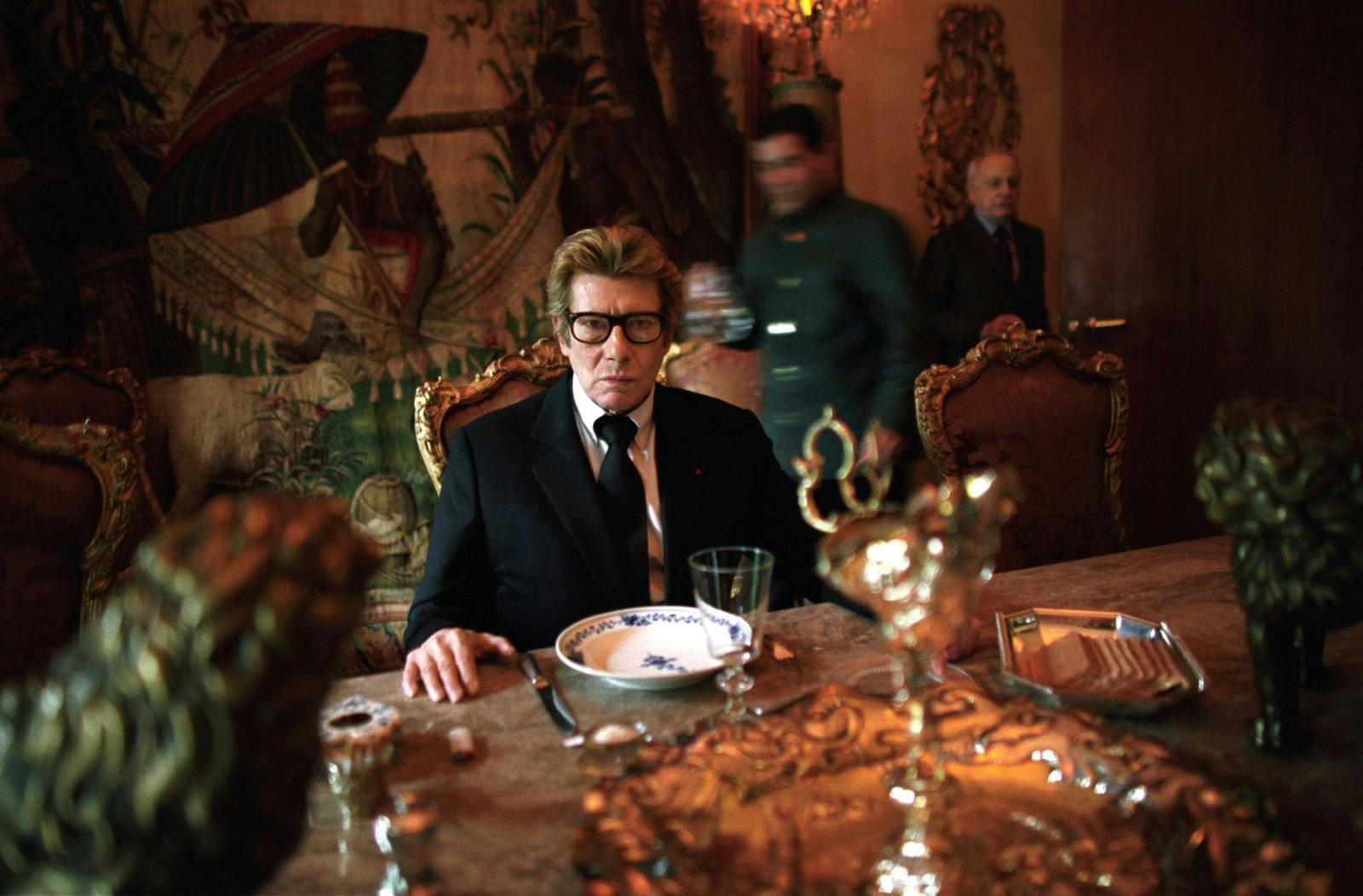 Saint Laurent dines at home on January 21, 2002, the day before his last fashion show. Pierre Bergé enters the room as a servant walks past.