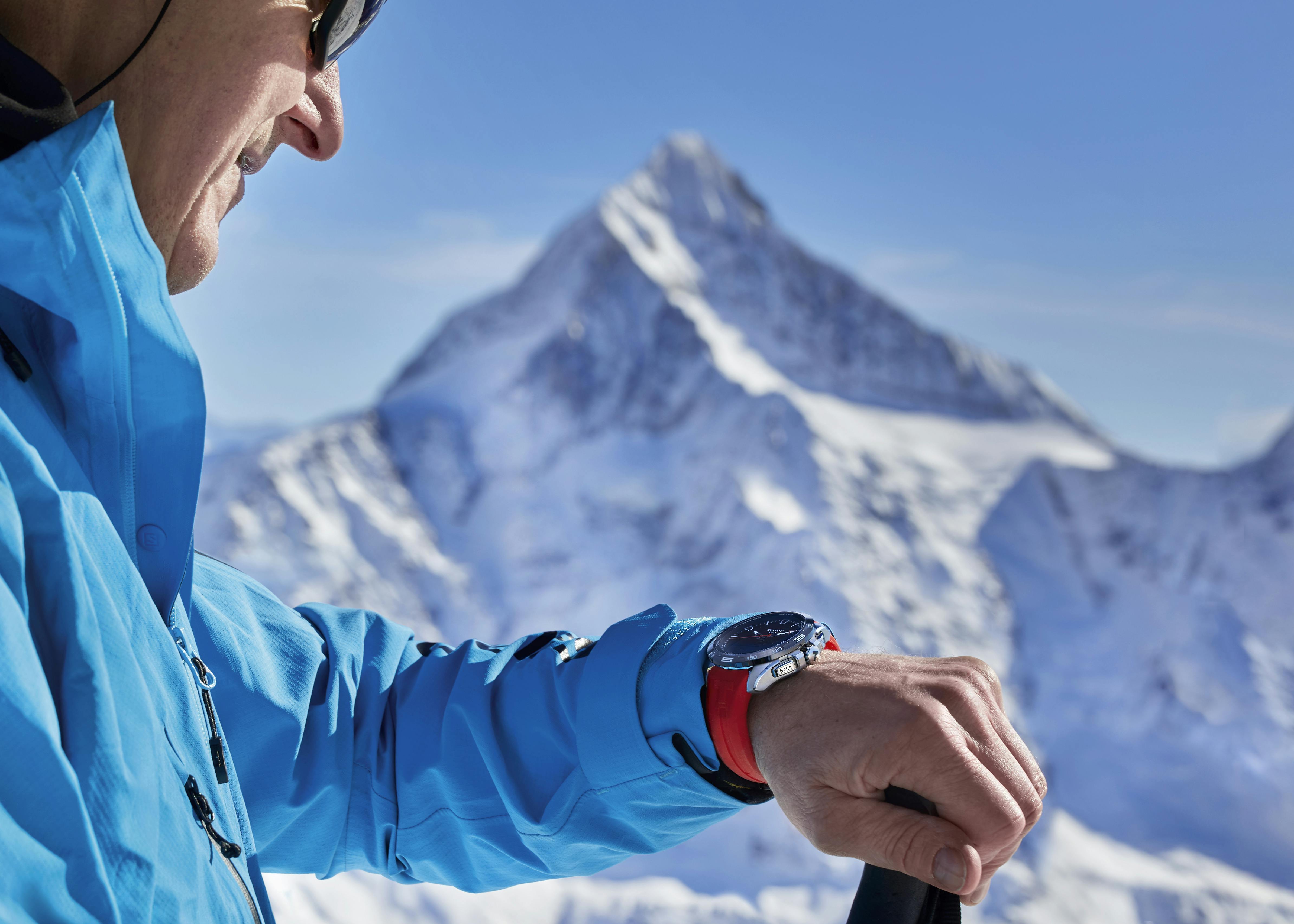 Un homme portant la smartwatch T-Touch Connect Solar de Tissot dans les Alpes suisses