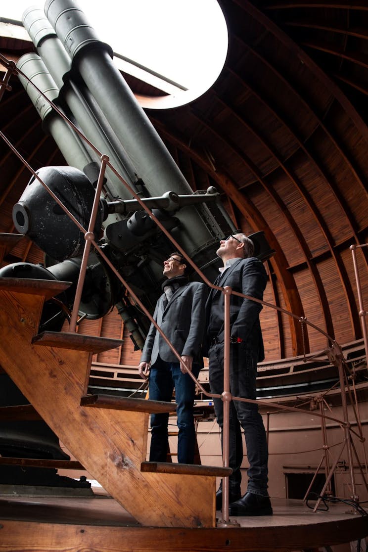 Two men looking up at a telescope