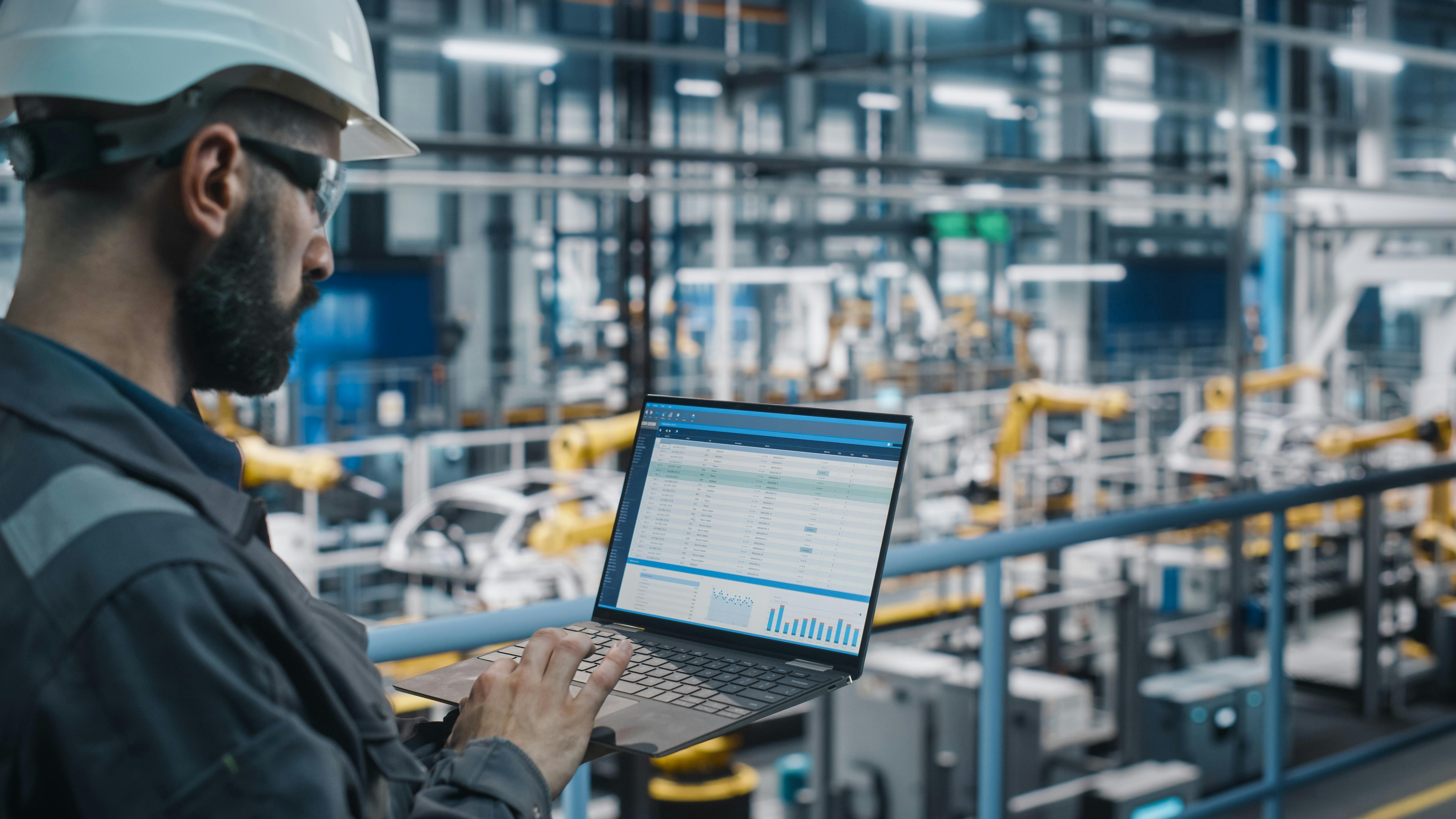 An engineer looking at data on his computer in a manufacturing plant