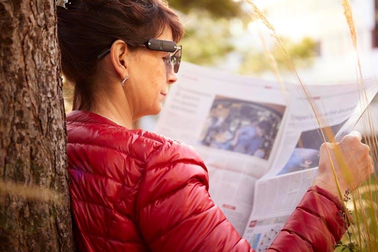 Female patient reading the newspaper and wearing standard glasses equipped with an Ulteem device