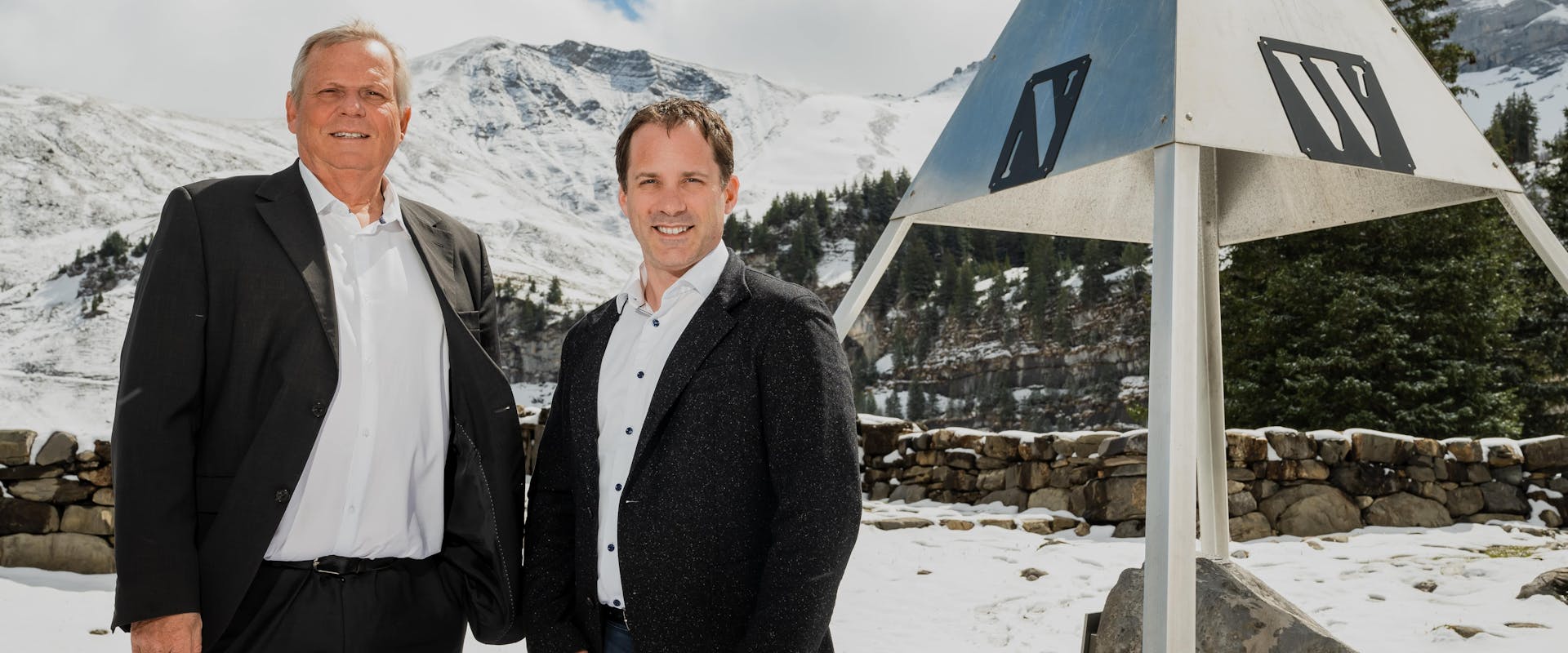 Two men standing next to a triangle shaped location marker in the geographical heart of Switzerland. 