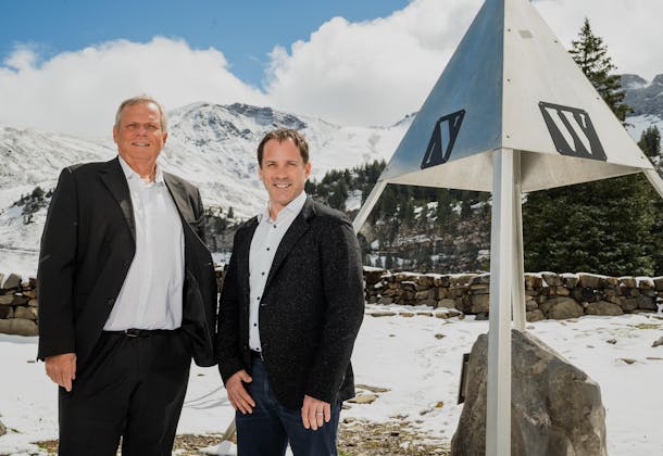 Two men standing next to a triangle shaped location marker in the geographical heart of Switzerland. 