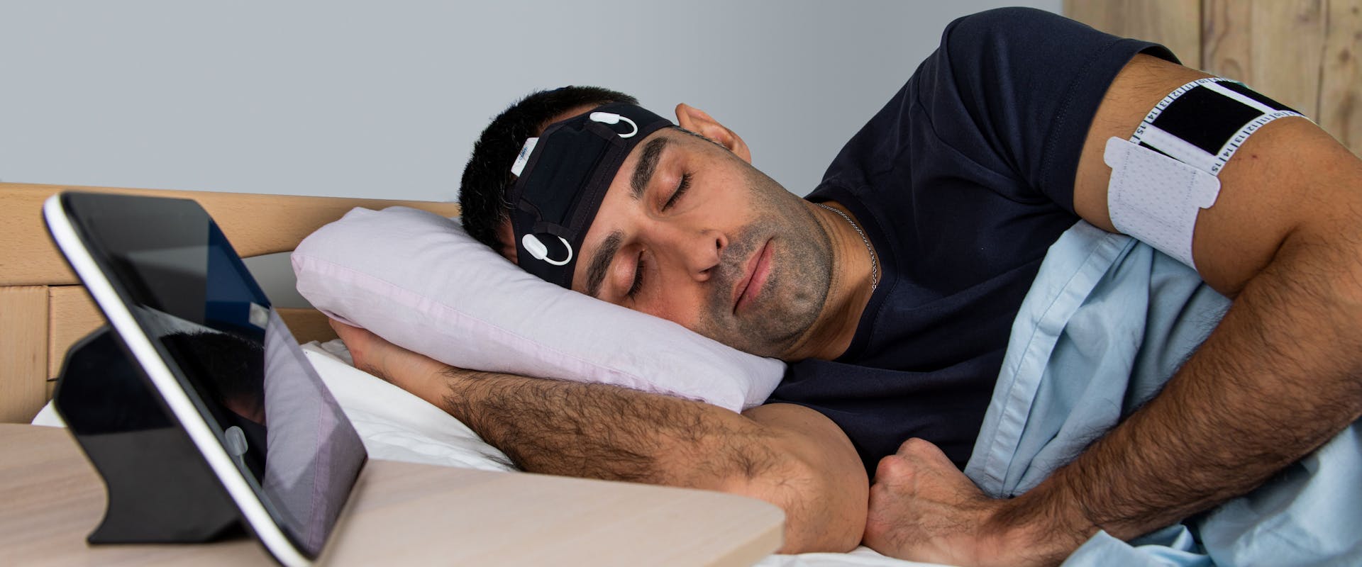 Male patient wearing a headband with a monitoring device during his sleep