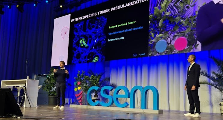 Two men on stage presenting in front of a screen