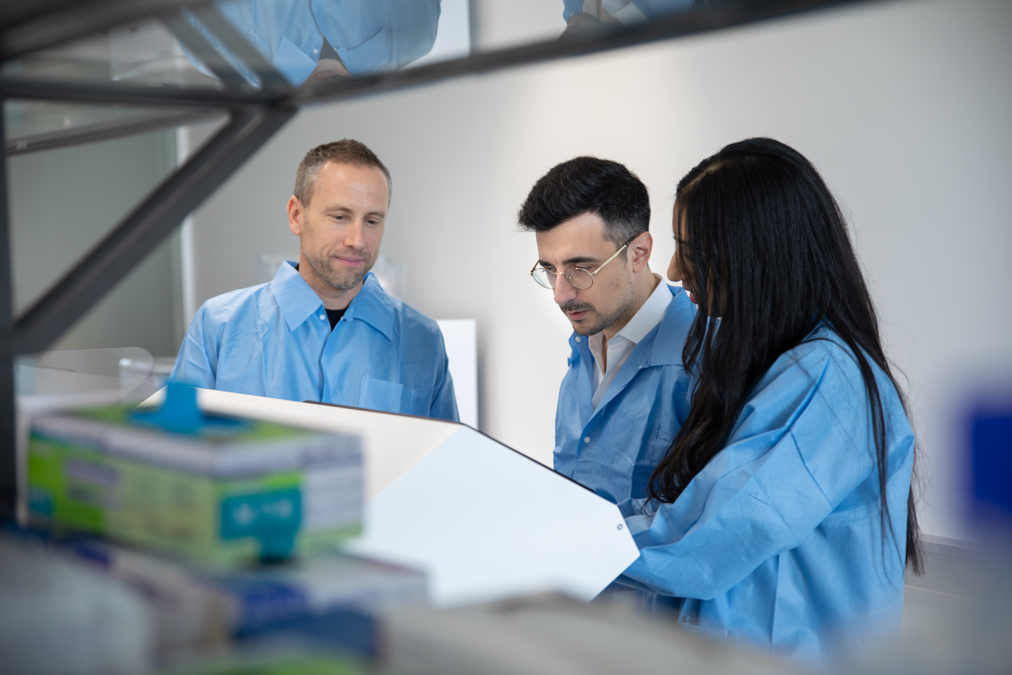 3 persons in a lab, looking at a technical device