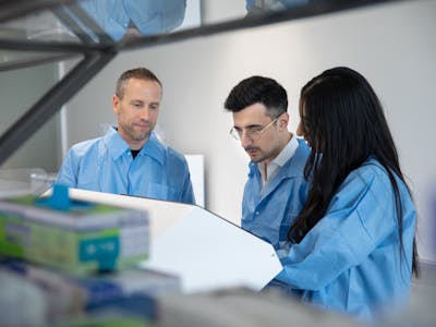 3 persons in a lab, looking at a technical device