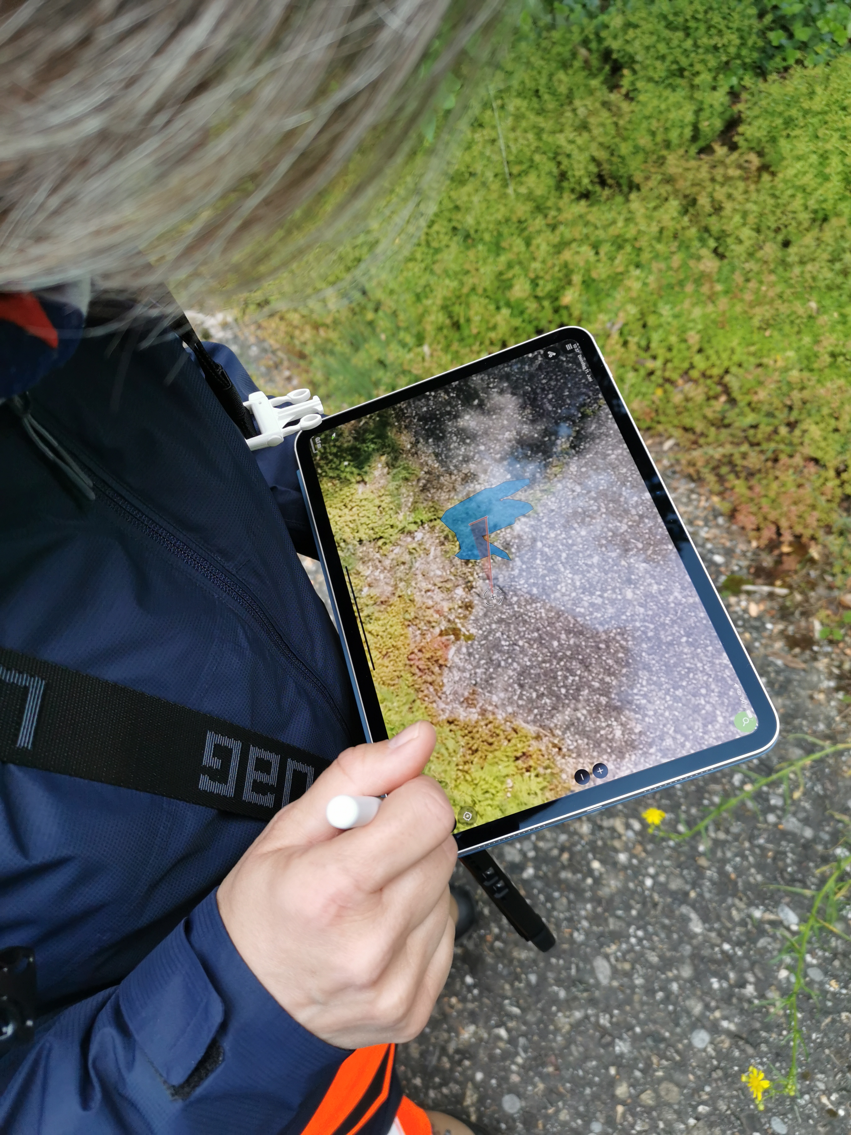 View onto a tablet displaying pictures taken by a drone with a human hand labeling the elements on the screen