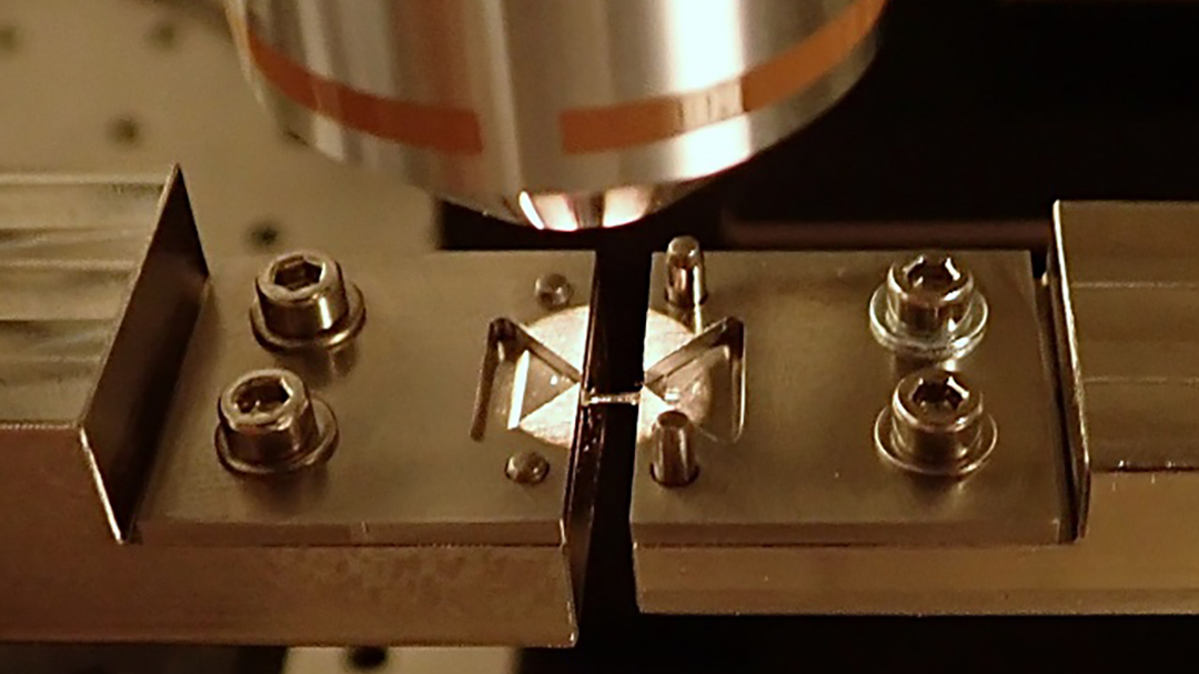 Close-up of a mesoscale tensile testing setup for characterizing 50–1000 µm samples.