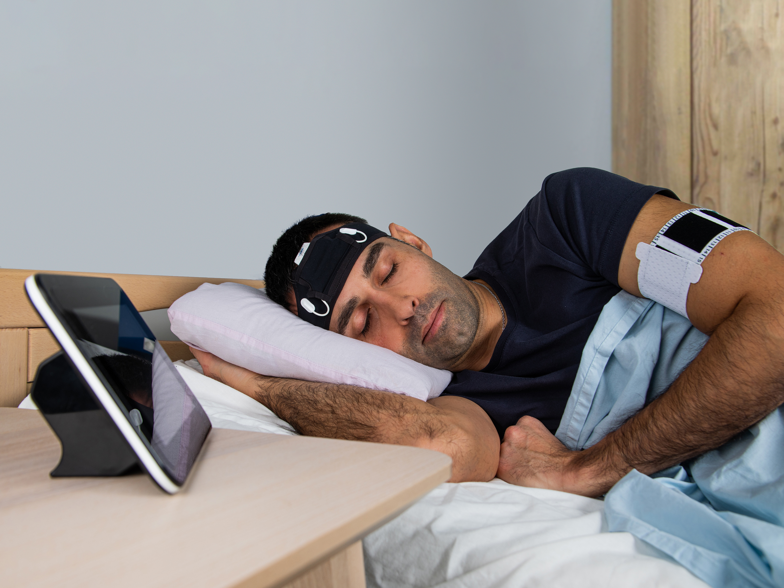 Sleep monitoring setup with multiple wearable sensors worn by a participant.