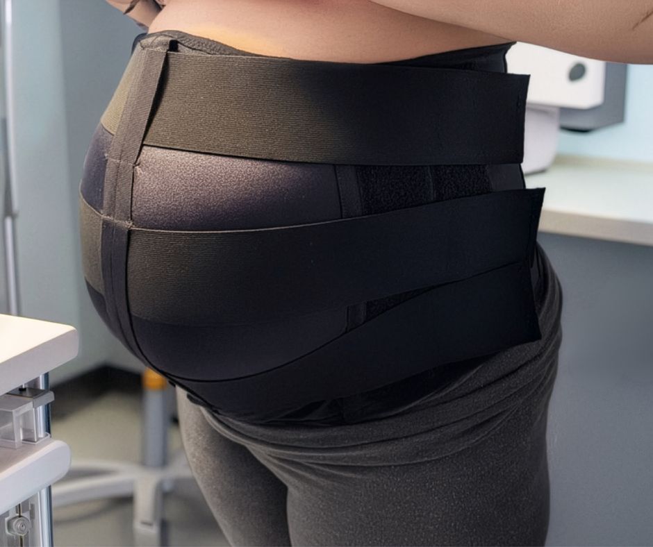 Side view of a person wearing a wide black VidaSense band around the lower torso or hips.