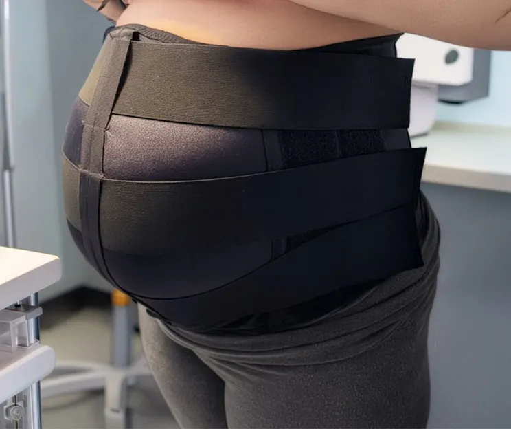 Side view of a person wearing a wide black VidaSense band around the lower torso or hips.