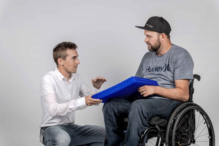 Engineer showing a specific technology to a person in a wheelchair