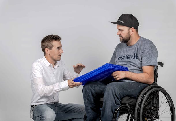 Engineer showing a specific technology to a person in a wheelchair