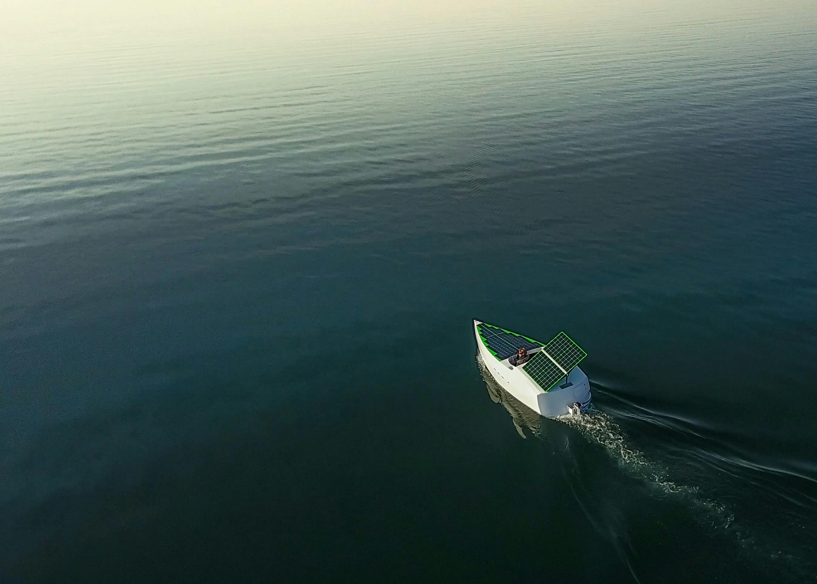 A small boat with a solar pannel sailing on water.