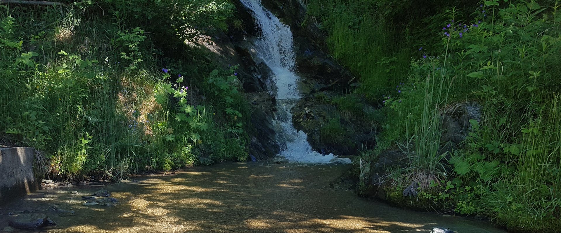 Blick auf einen kleinen Wasserfall in einem Berggebiet