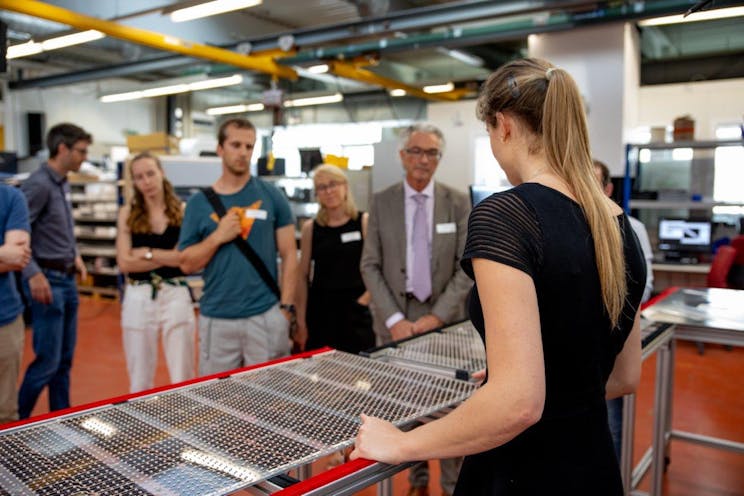 Engineer woman showing PV panels to an audience of guests and journalists